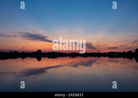 Bunte Wolken nach Sonnenuntergang Spiegelbild im See Wasser Stockfoto