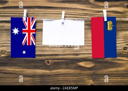 Hängenden Flaggen von Heard und Mcdonald Inseln und Liechtenstein Seil mit wäscheklammer mit Kopie Raum befestigt auf weißem Papier auf Holz backgro Stockfoto
