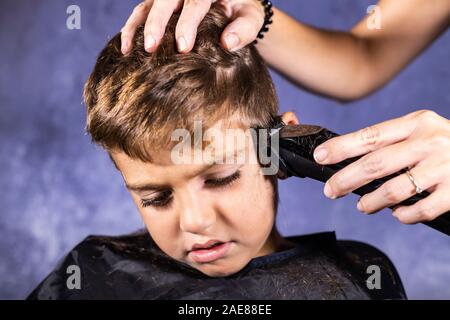 Kleinen Jungen bekommen einen Haarschnitt mit einer Schneidemaschine Stockfoto