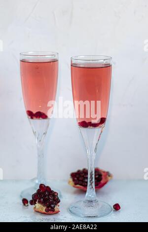 Urlaub Granatapfel trinken. Rosa Wein. Im Hintergrund sind Granatapfel Schichten. Weißer Hintergrund. Champagner. Für das neue Jahr. Weihnachten. Im Vordergrund. Stockfoto