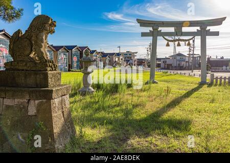 Bei Sonnenuntergang, komainu und torii Tor an der Stelle des jährlichen Okaeri (Willkommen zu Hause) Festival, Mikawa, Japan. Ein torii markiert die Grenze zwischen den pro Stockfoto