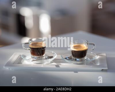 Zwei schöne Glas Kaffee Tasse legt, gefüllt mit Kaffee auf einer Arbeitsplatte Nahaufnahme Stockfoto
