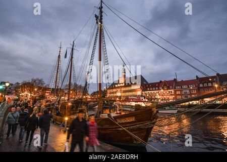 Emden, Deutschland. 07 Dez, 2019. Weihnachtliche Atmosphäre an der Emder Engelkemarkt. Besucher auf dem Weihnachtsmarkt schlendern Sie durch die festlich beleuchtete Schiffe entlang der Ratsdelft. Im Hintergrund das festlich beleuchtete Emder Rathaus. Credit: Karsten Klama/dpa/Alamy leben Nachrichten Stockfoto