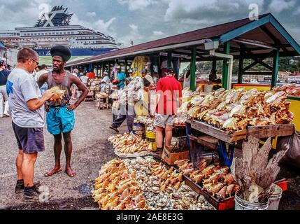 St. George's, Grenada. 6. Dezember, 2019. Eine touristische untersucht Muscheln zum Verkauf, mit der lokalen Hausierer, in einem bunten Markt in St. George's, der Hauptstadt der karibischen Insel Grenada. Als die Gewürzinsel Grenada bekannt, ist ein beliebtes Touristenziel. Credit: Arnold Drapkin/ZUMA Draht/Alamy leben Nachrichten Stockfoto