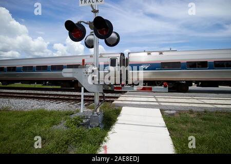 Amtrack Bahnhof Überqueren der Straße hinter Barrieren am Bahnhof Fußgänger Bahnübergang in der Nähe von Park am Ontariosee kissimmee Florida USA Stockfoto