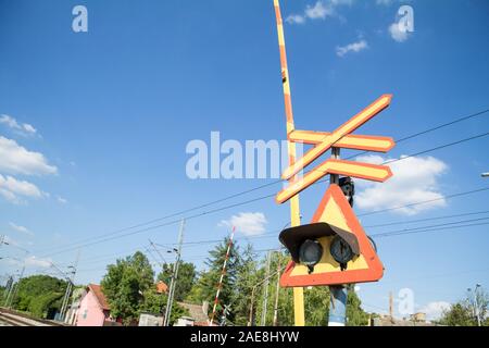 Bahnübergang Zeichen, genannt crossbuck, saltire oder Saint Andrews Kreuz, an einer Straße, die eine Eisenbahnstrecke in Pancevo, Serbien Kreuze stehen, mit einer Bar Stockfoto