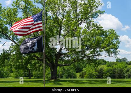 Die amerikanische Flagge und POW/MIA Fahne fliegt im Wind an einem Friedhof über das Memorial Wochenende in Humansville, Missouri. Stockfoto