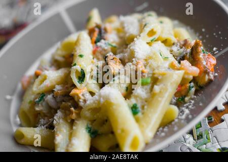 Nudeln mit Meeresfrüchten und Petersilie top mit geriebenem Parmesan bestreut Stockfoto