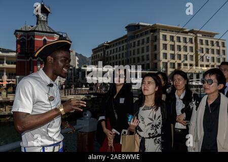 Ein Reiseleiter Chaperone chinesischen Touristen in Kapstadt Waterfront District. Südafrika ist auf der Suche nach China als Quelle des Tourismus Einnahmen Stockfoto