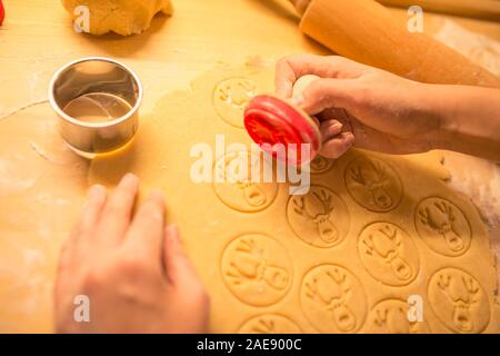 Die Hand des Kindes die traditionelle Weihnachtsplätzchen. Gewürze auf dem Tisch - Anis, Kardamom, Zimt, Nelken. Rohen Teig und Messer für Holiday cookies Stockfoto