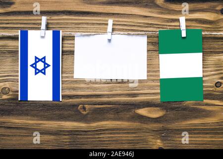 Hängenden Flaggen Israels und Nigeria zu Seil mit wäscheklammer mit Kopie Raum befestigt auf weißem Papier auf Holz- Hintergrund. Diplomatische Beziehungen b Stockfoto