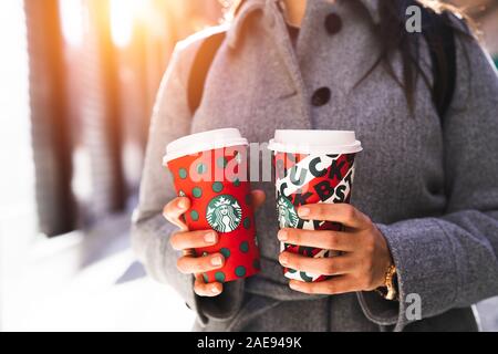 New York, USA - Dezember 5, 2019: Nahaufnahme eines Jungen Business Frau mit zwei hohen Weihnachten Starbucks Kaffee auf der Straße. Starbucks ist der worl Stockfoto