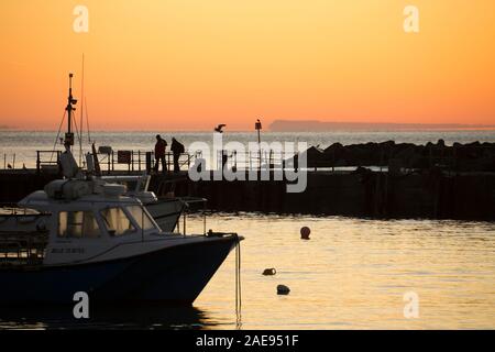 Sonnenaufgang über dem Hafen in Lyme Regis mit der Isle of Portland im Hintergrund. Lyme Regis ist auf der Heritage Coast oder Jurassic Coast gelegen, ein Stockfoto