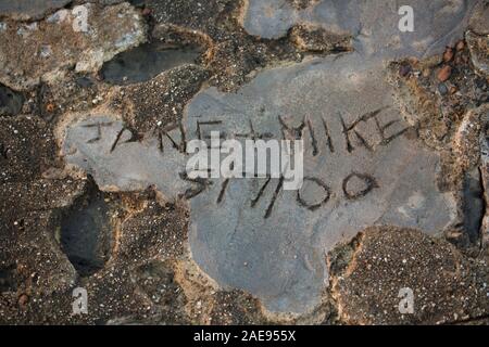 Namen, die in Zement auf dem der Cobb in Lyme Regis Hafen geätzt wurden. Lyme Regis ist auf der Heritage Coast oder Jurassic Coast gelegen, und die Stockfoto