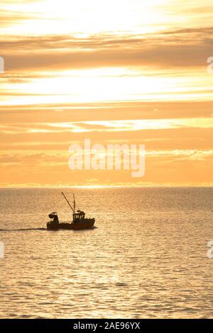 Eine Küstenfischerei Schiff, das den Hafen von Lyme Regis, heraus, in der Dämmerung an einem frostigen Morgen im Anfang Dezember 2019 verlassen hat. Lyme Regis Stockfoto