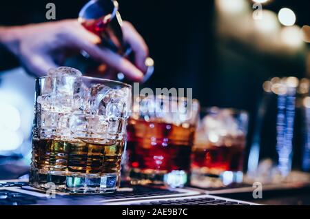 Der Barkeeper gießt Cocktail in Gläser. Brille mit roten Cocktail in einem altmodischen Glas Stockfoto