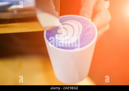 Closeup Bild der männlichen Händen gießen Kokosmilch und Vorbereitung blau Matcha Latte. Blue latte Art Stockfoto