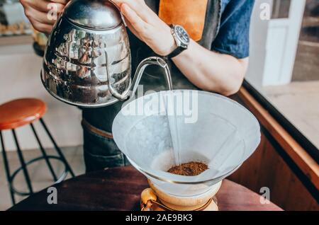 Barista Vorbereitung filter Kaffee im Freien. Männliche barista gießt kochendes Wasser aus dem Wasserkocher Stockfoto