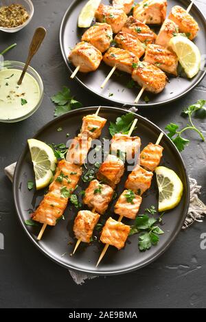 Gegrillter Lachs Kebab. Grill lachs Spieße auf dunklem Stein Hintergrund. Stockfoto