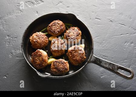 Nahaufnahme der gebratenen Hackfleisch Schnitzel in der Pfanne über schwarzen Stein. Stockfoto