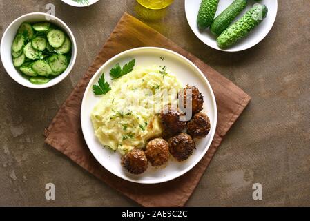 Hackfleisch Schnitzel mit Kartoffelbrei auf weißen Platte über braunen Hintergrund. Ansicht von oben, flach Stockfoto