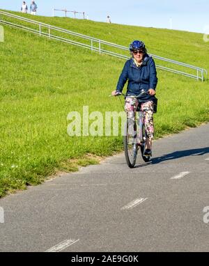 Radfahrerin auf einem Radweg auf einem Deich Cuxhavener Niedersachsen Deutschland. Stockfoto