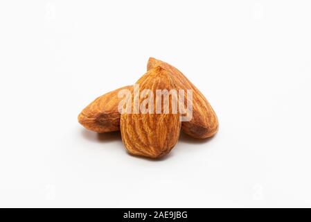 Nahaufnahme von drei geröstete Mandeln auf einem weißen Hintergrund. Stockfoto