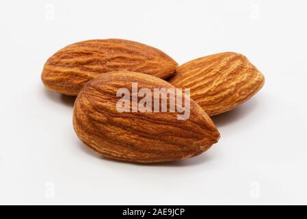 Nahaufnahme von drei geröstete Mandeln auf einem weißen Hintergrund. Stockfoto