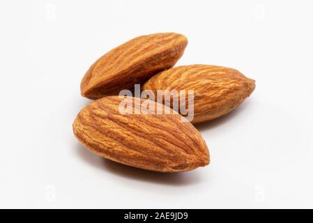 Nahaufnahme von drei geröstete Mandeln auf einem weißen Hintergrund. Stockfoto