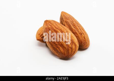 Nahaufnahme von drei geröstete Mandeln auf einem weißen Hintergrund. Stockfoto