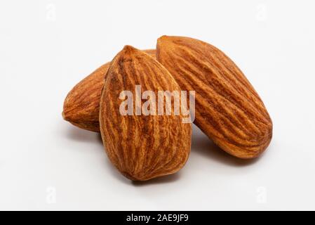 Nahaufnahme von drei geröstete Mandeln auf einem weißen Hintergrund. Stockfoto