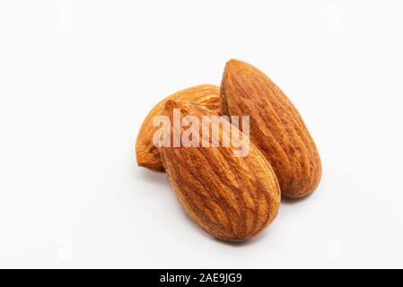 Nahaufnahme von drei geröstete Mandeln auf einem weißen Hintergrund. Stockfoto