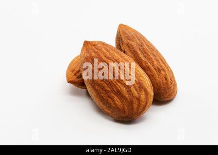 Nahaufnahme von drei geröstete Mandeln auf einem weißen Hintergrund. Stockfoto
