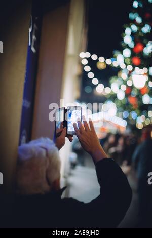 Straßburg, Frankreich - Dez 20, 2016: Rückansicht des älteren Mann mit weißem Haar die Bilder auf dem Smartphone des jährlichen Weihnachtsmarkt in Straßburg Place Kleber Stockfoto