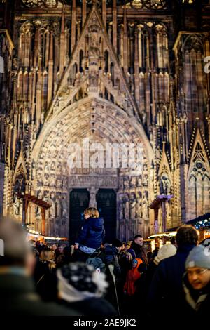 Straßburg, Frankreich - Dez 20, 2016: Ansicht der Rückseite des jungen Mann auf Vater shoulers mit Notre-Dame de Strasbourg Kathedrale im Hintergrund während der Weihnachtsmarkt Stockfoto