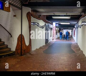 Menschen, die im Tunnel gehen, verbinden Bahnsteige am Bahnhof Uelzen, der vom Architekten Friedensreich Hundertwasser Niedersachsen Deutschland renoviert wurde. Stockfoto