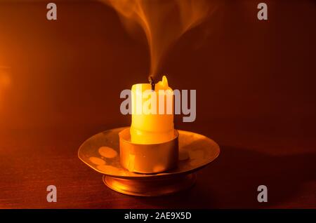 Erloschene Kerze auf einem Holztisch in der Nacht Stockfoto