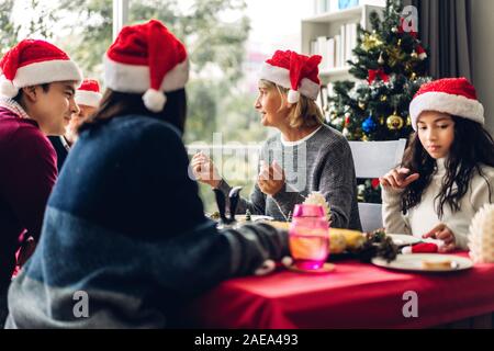 Portrait von Happy Big Family feiern santa Hüte zusammen Spaß haben und Mittagessen Ausgabe Zeit zusammen genießen in der Weihnachtszeit zu Hause Stockfoto