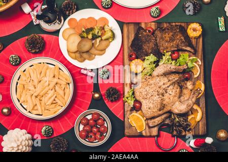 Blick von oben auf die leckere gebackene Geröstete ganze gebratene Hähnchen und Salat mit Weihnachten Dekoration auf der Weihnachten thematische Abendessen in Tabelle Stockfoto