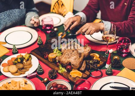 Glückliche Familie sind Sie zum Abendessen mit leckeren gebackenen gerösteten Ganzen gebratenes Huhn und Weingläser mit Weihnachten Dekoration auf der Weihnachten thematische Abendessen Stockfoto