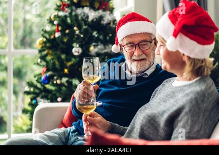 Senior Paar entspannen Reden und trinken Weingläser zusammen auf dem Sofa im Wohnzimmer zu Hause. Ruhestand paar Konzept Stockfoto