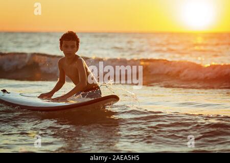 Junge Surfer bereit für die Fahrt mit dem Ocean Wave gegen beautifull sinset Licht Stockfoto