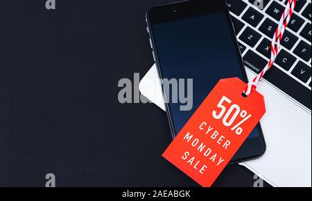 Cyber Monday Verkauf Text auf rotem Tag haben smart phone über Laptop mit rotem Hintergrund Stockfoto