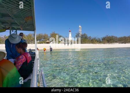 Lady Elliot Island Australien - 25. November 2019; Menschen an Bord Tauchboot, während andere sind, betreten und verlassen Wasser mit Leuchtturm und Strand hinterg Stockfoto