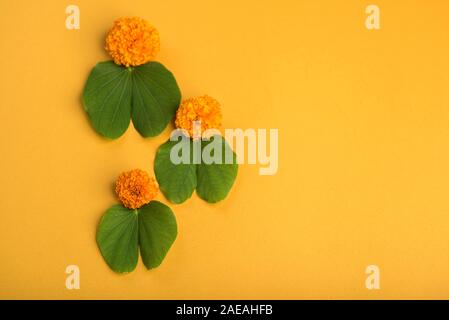 Indian Festival Dussehra, anzeigen Golden Leaf (Bauhinia racemosa) und Ringelblume Blüten auf gelbem Hintergrund. Stockfoto