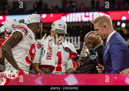 Indianapolis, Indiana, USA. 8 Dez, 2019. Ohio State Buckeyes Quarterback Justin Felder (1) ist die MVP-Trophäe durch ehemalige Ohio Buckeye Archie Griffin Nach dem Gewinn des Spiels zwischen der Wisconsin Dachse und die Ohio State Buckeyes im Lucas Oil Stadium, Indianapolis, Indiana, ausgezeichnet. Credit: Scott Stuart/ZUMA Draht/Alamy leben Nachrichten Stockfoto