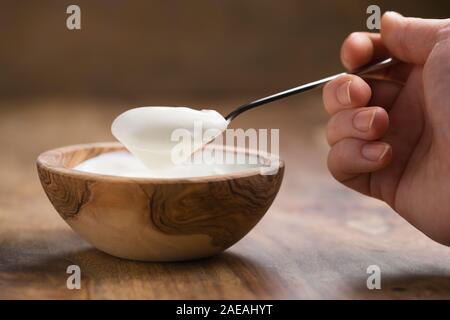 Pov-shot von jungen weiblichen Hand mit vollen Löffel Joghurt am Tisch sitzen, flacher Fokus Stockfoto