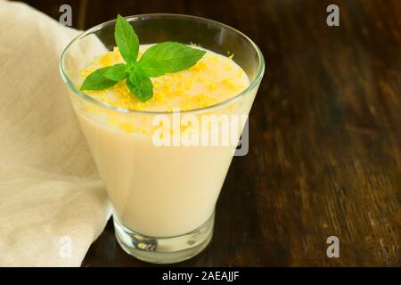 Vanille Mousse oder Pudding mit Zitronenschale und Minze im Glas Schale dekoriert. Close-up. Stockfoto