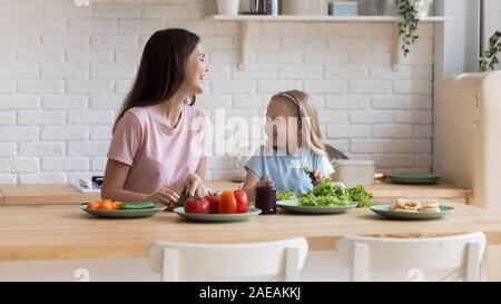 Mutter lehrt kleine Tochter im Vorschulalter kochen Abendessen in der heimischen Küche Stockfoto