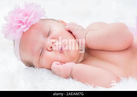 Cute Baby trägt ein rosa Blume Krone in einer weißen Decke liegt. Nahaufnahme. Stockfoto